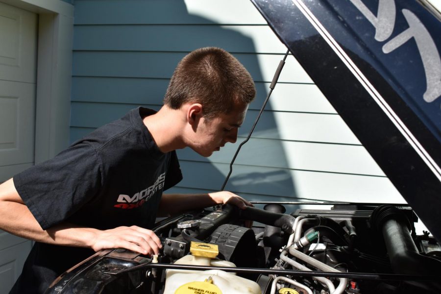 Adam Koecke pours over a car engine.