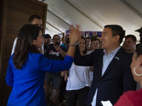 Presidential candidates Andrew Yang and Tulsi Gabbard high five next to Tulsi 2020 campaign booth.