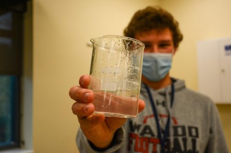 Junior Parker Klein holds a beaker filled with mostly water and a small amount of oil floating on the top. This was all that their group could extract from the water, without leaving it stuck to their model. 