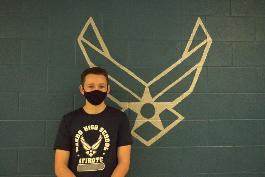 Senior Zane Gillies posing in front of the Air Force service symbol in his JROTC uniform.

