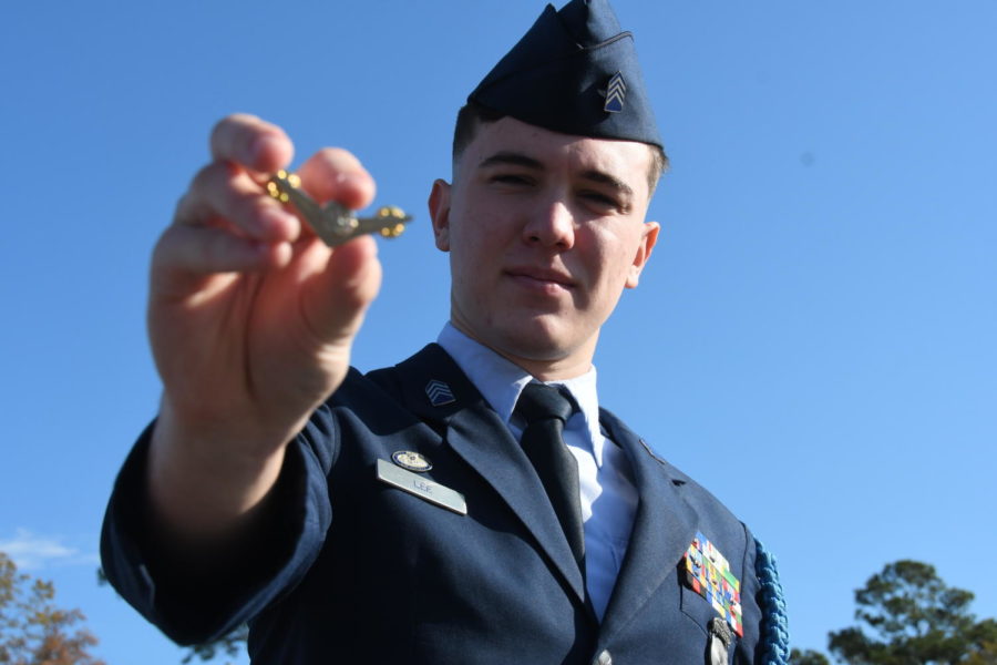 After being deeply inspired by his father, Grant Lee proudly holds up his wing pin that symbolize having a pilots license.