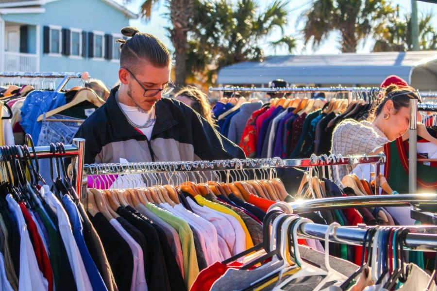 A man looks through racks of vintage, second hand clothing at a flee market called Eight-Four-Flee.