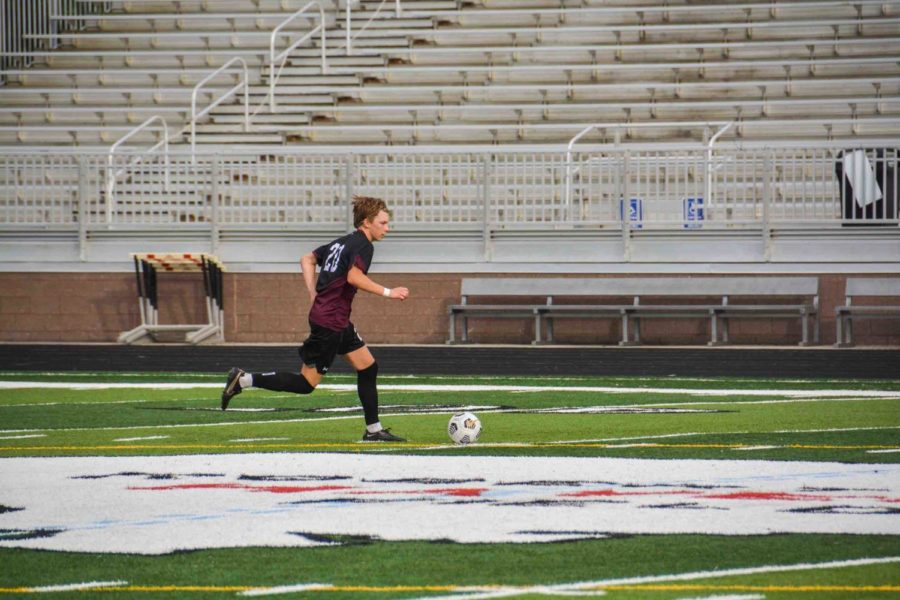 Junior Jack Pottieger runs across the field with the soccer ball.