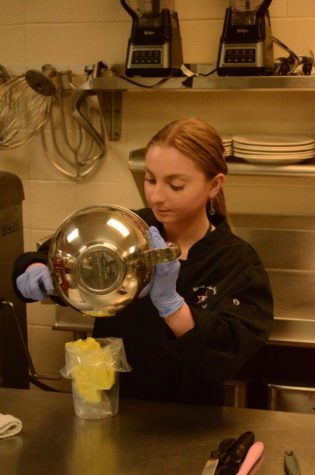 Culinary program Chef, Molly Gordan, is guiding a student in what to add into a new sauce. Helping the student  mix as they add zest from a lemon into the bowl. 