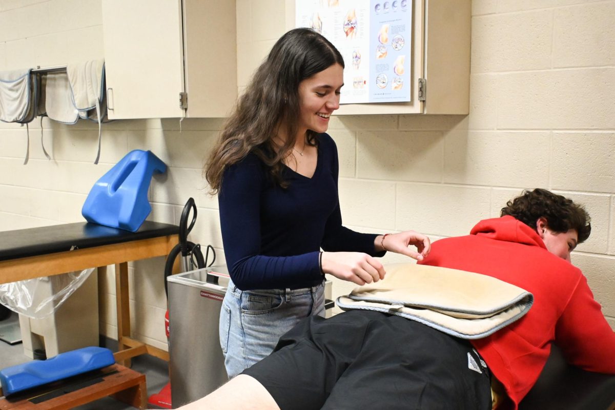 Senior Leia Eisen places a heating pad on a patient during her sports medicine internship. “The requirement for the internship was 120 hours. Having KLS while also balancing the internship put pressure on me to help with my team but also juggle my academics as well. My athletic trainers were very helpful on letting me put academics first 
however I still felt bad missing out on helping my team,” Eisen said