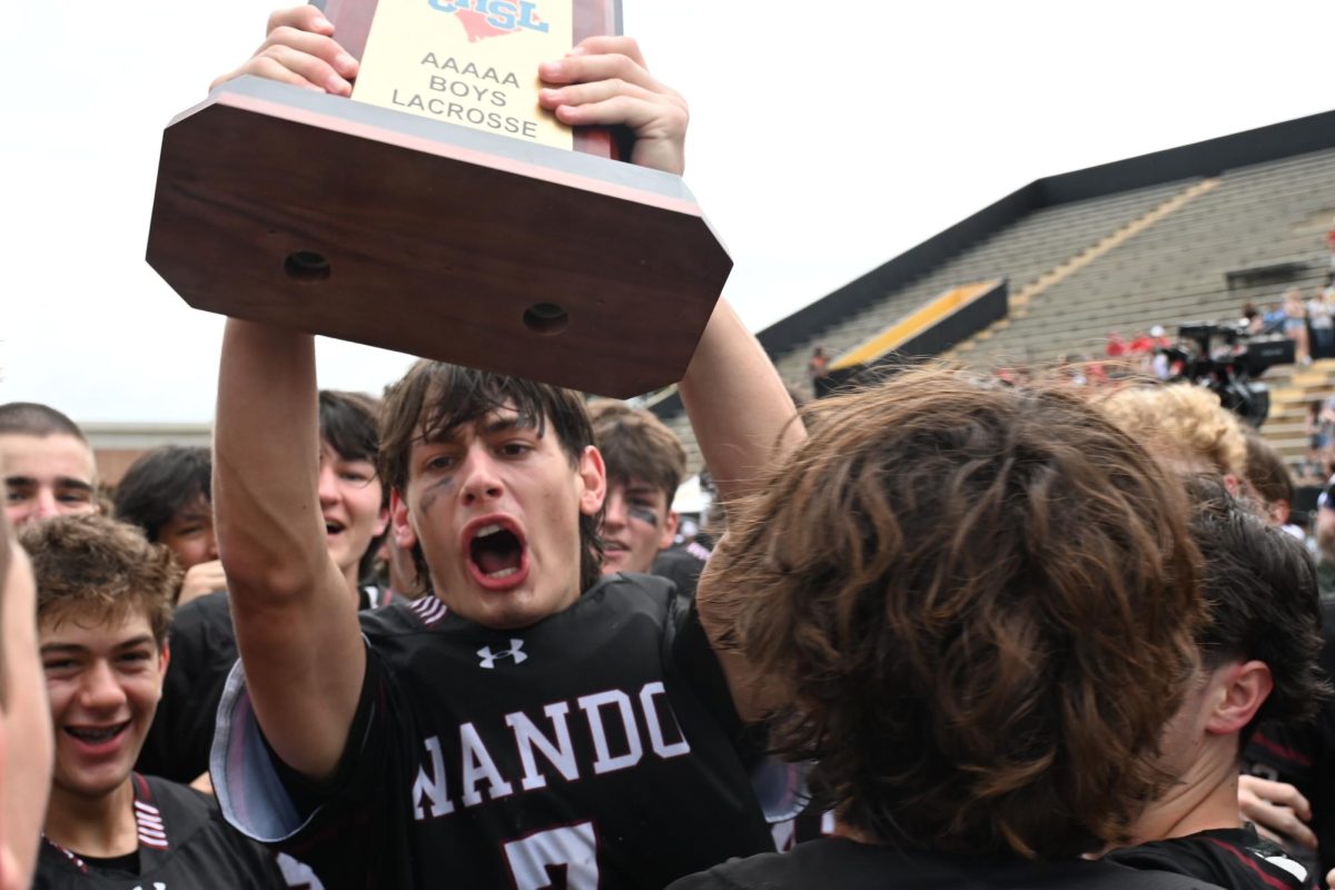 Senior Bragg McConnell holds high the state championship trophy following Wando’s win over Nation Ford.