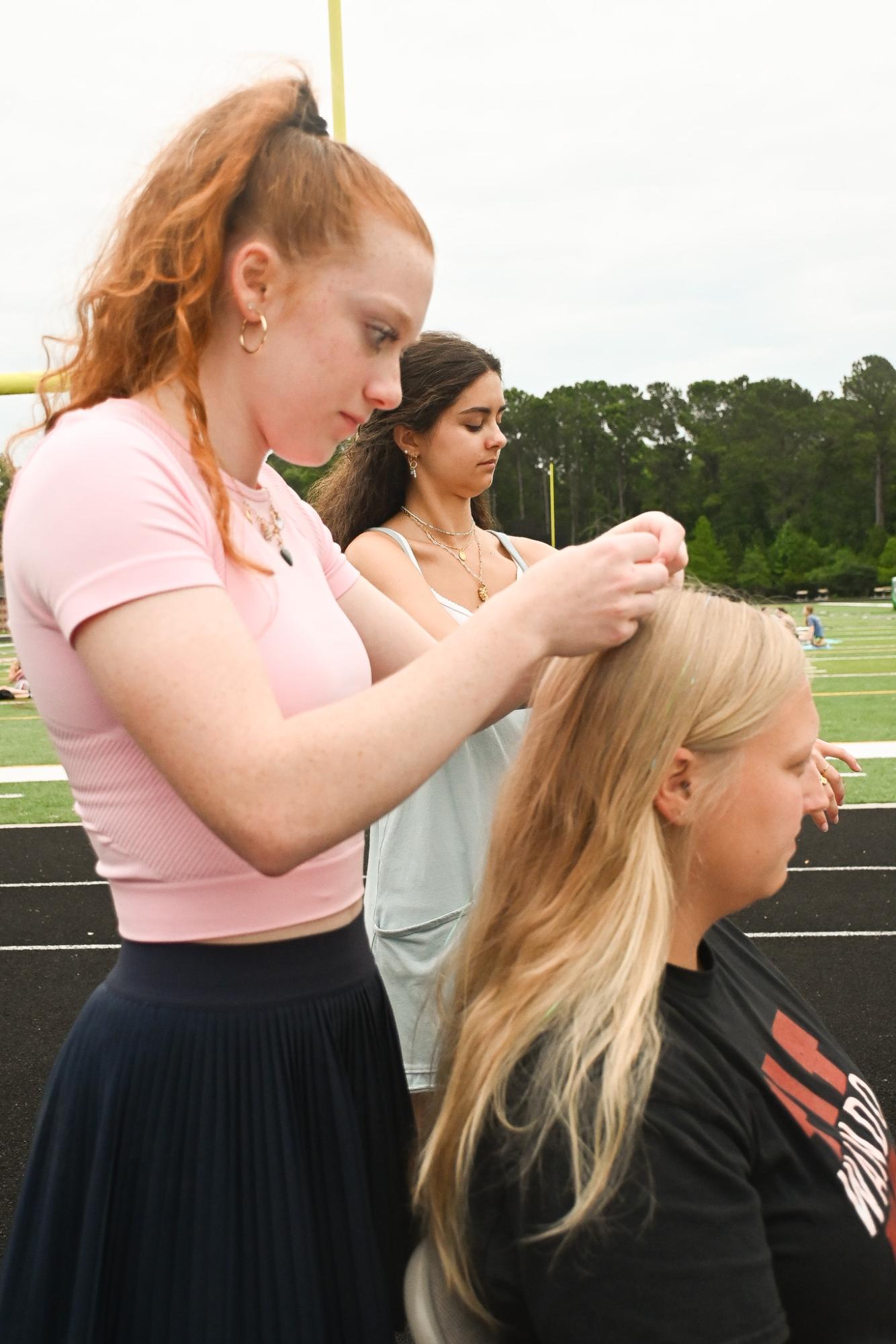 Student Council spirit chair Kelsey Miller puts fairy braids into teacher
Cori Jarotski’s hair. Fairy hair braids were available throughout the event
for participants, provided by Student Council.