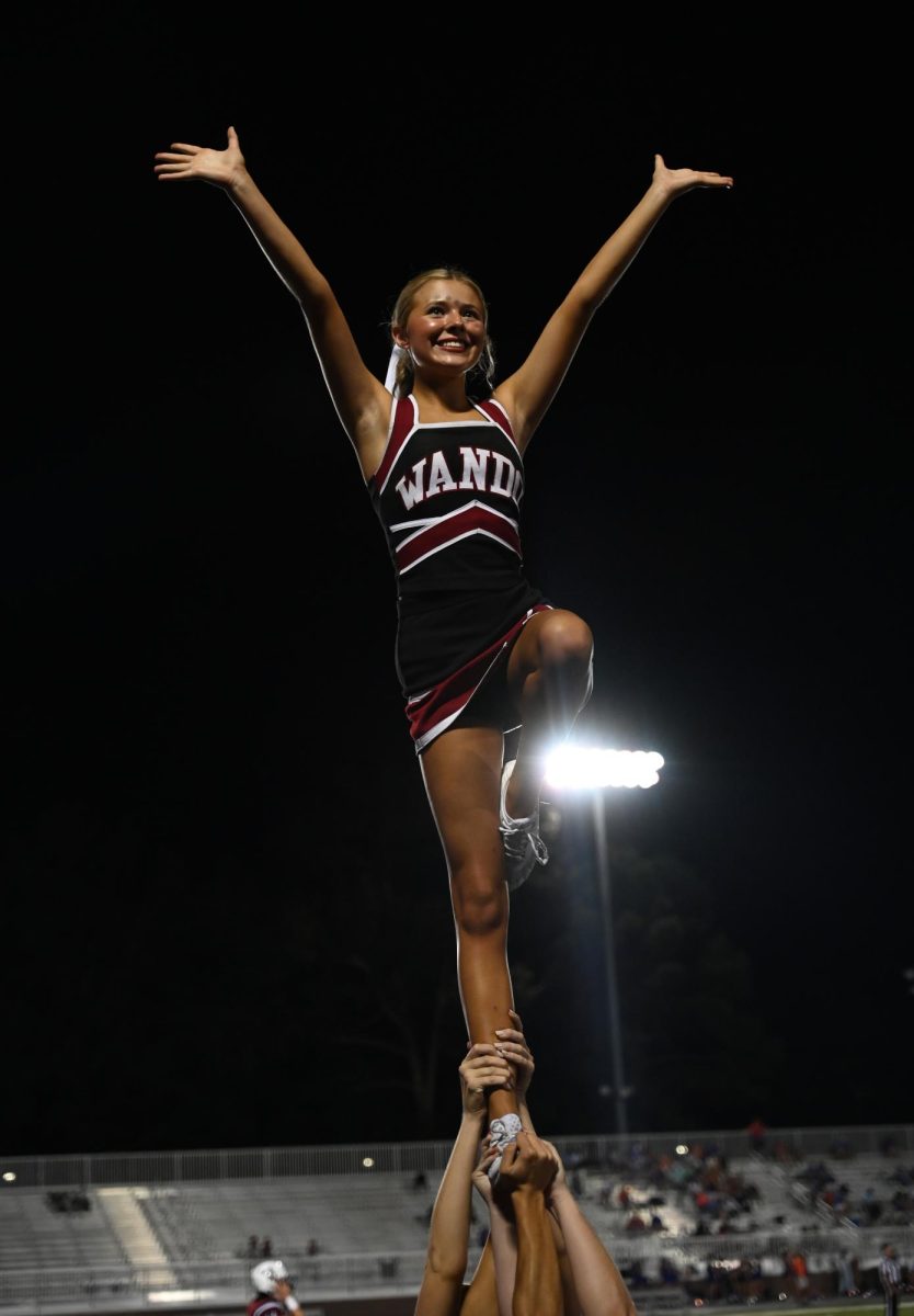 Cheerleaders lift their teammate into the air for a preformance.