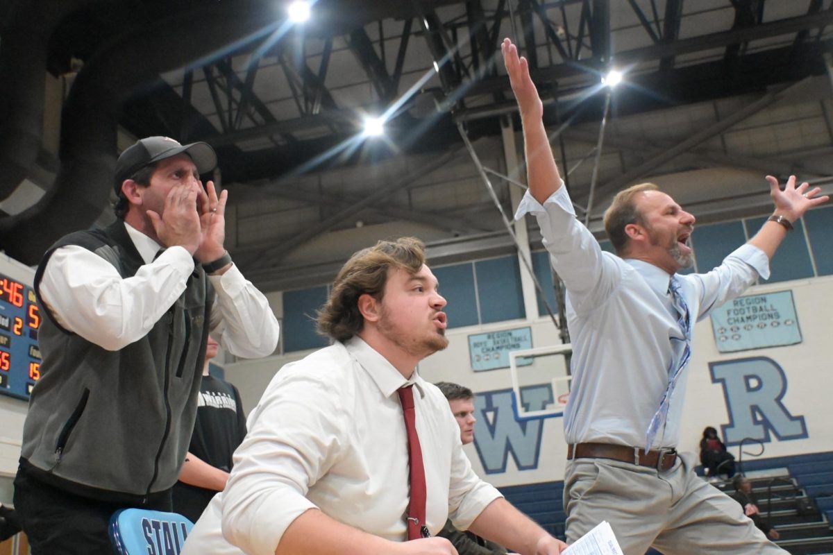 Wrestling coaches Schneider, Rocco, and Craeton all up and cheering on their Varsity athletes 