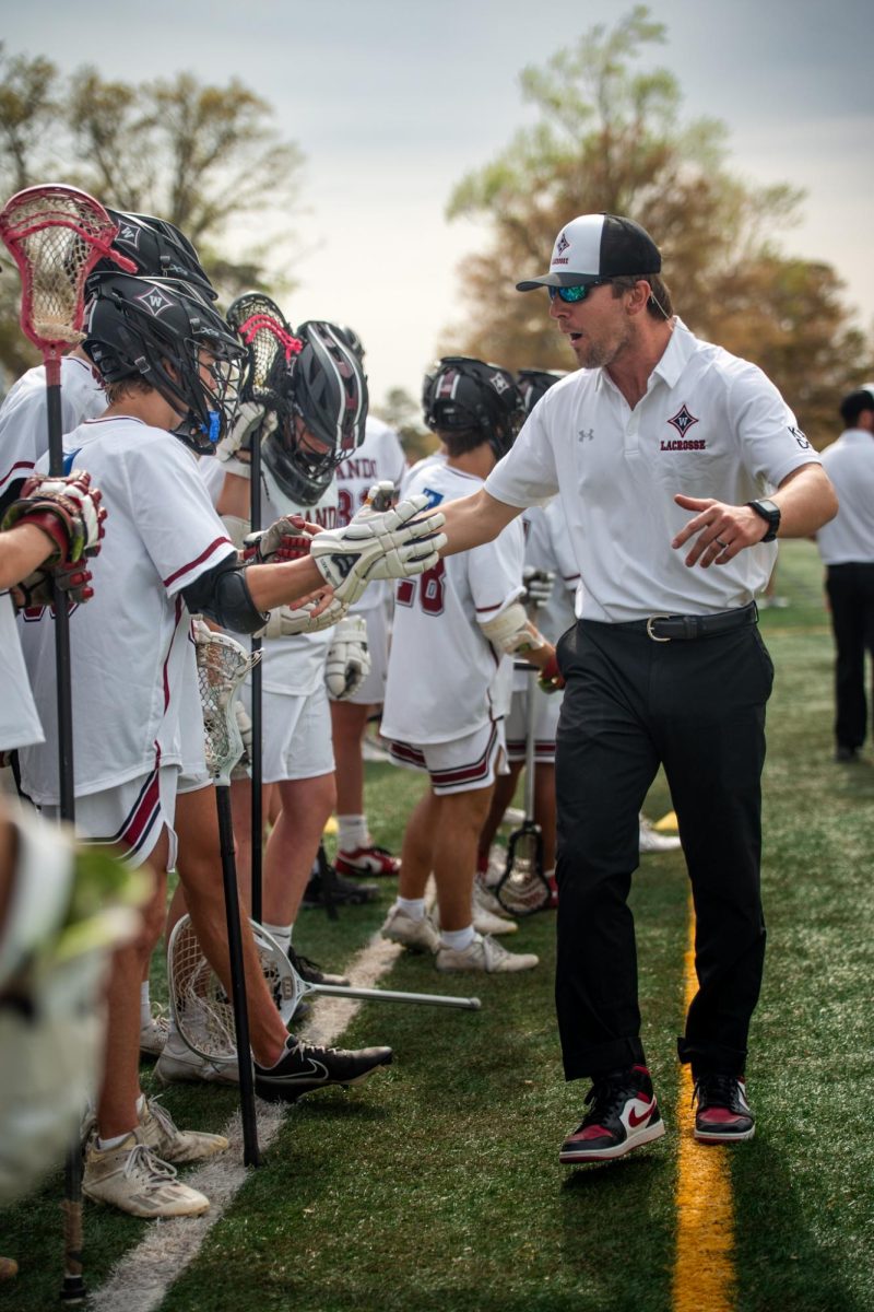 Offensive Coordinator Jeff Mayer exchanges high fives with players on the sideline, a tradition he has built with the team that happens after every goal.