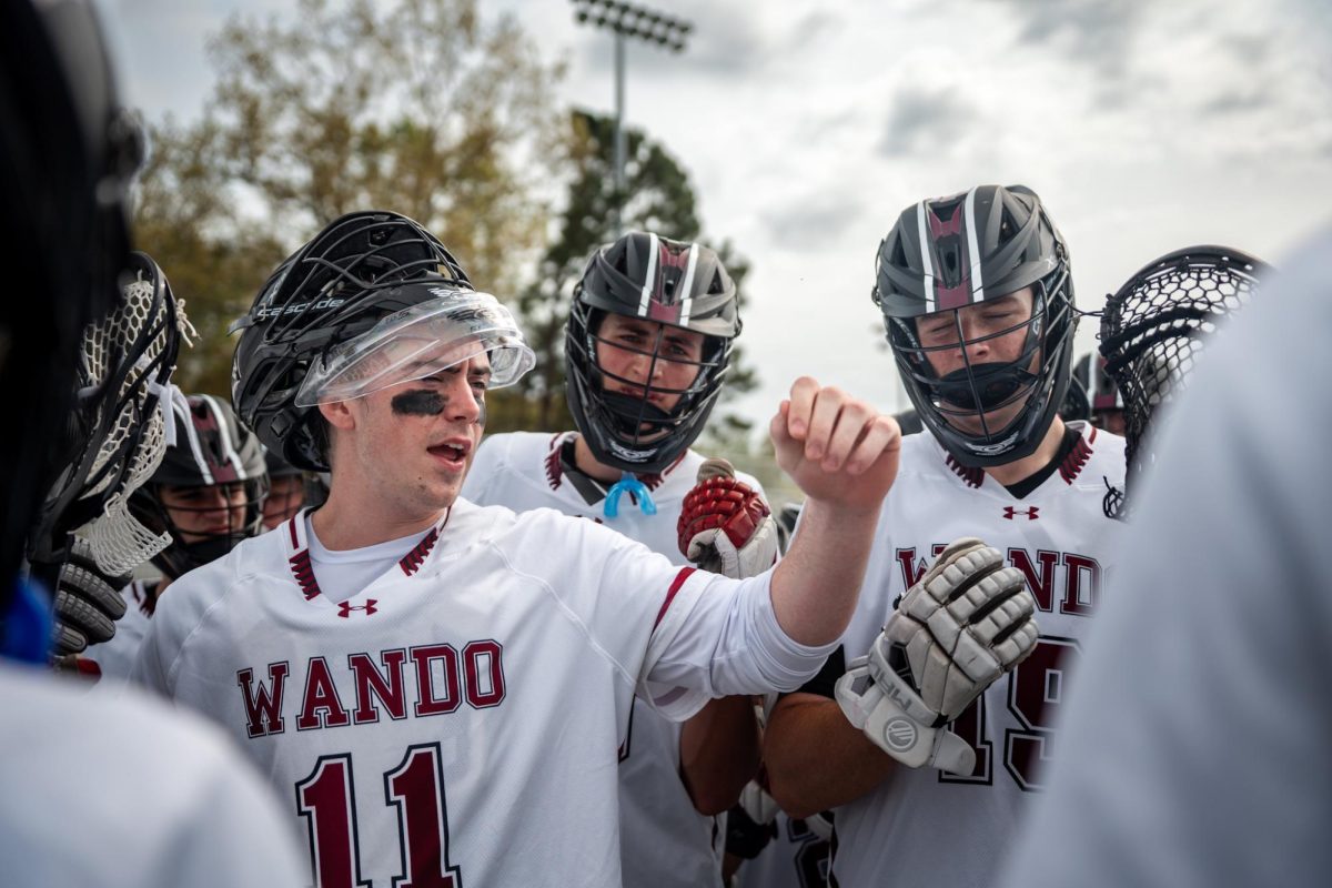 Senior goalie Connor Kraemer raises his fist with the team at the end of a huddle before the end of a timeout.