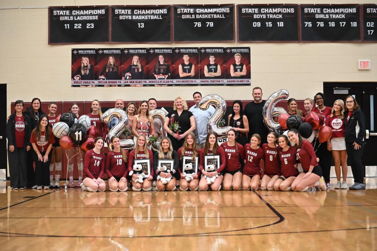 The Wando Varsity Volleyball team, their coaches, and the parents of the seniors gather together to take a photo.